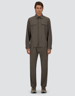 Full-body image of a man wearing a gray utility shirt with two chest pockets and matching straight-leg pants, beige sneakers