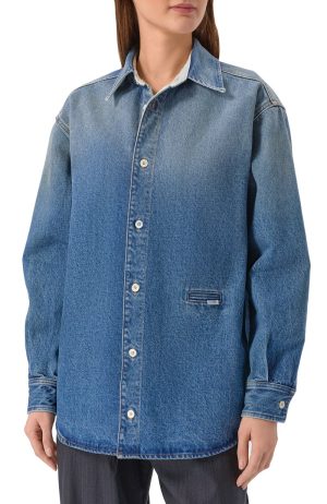 Light wash denim button-up jacket worn by a person, featuring a collared neckline, long sleeves, and a small front welt pocket on the lower left.