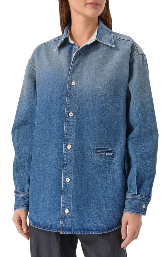 Light wash denim button-up jacket worn by a person, featuring a collared neckline, long sleeves, and a small front welt pocket on the lower left.
