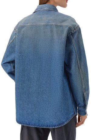 Back view of a person wearing an oversized blue denim jacket with a curved hem and visible stitching.