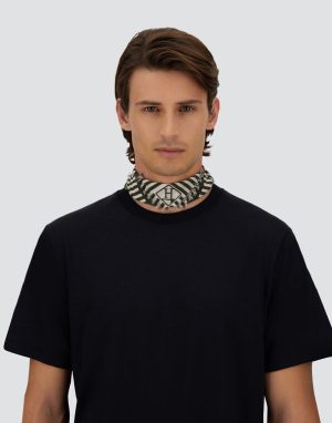 Young man in a black T-shirt with a black-and-white patterned neck scarf against a light gray background.