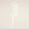 White scarf draped over a hanger against a pale beige background in a minimalist display