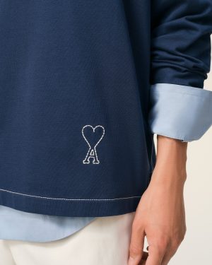 Close-up of navy fabric with a small white stitched heart outline near the hem and a light blue cuff nearby.