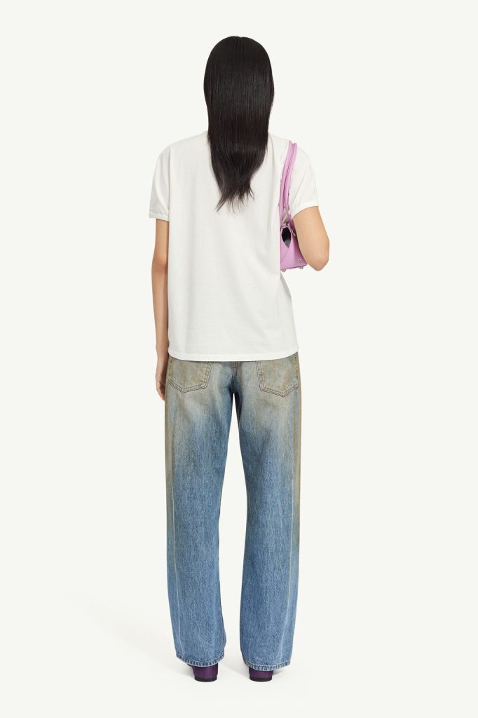 Back view of a person wearing a white T-shirt and loose blue jeans, carrying a pink handbag over the shoulder.