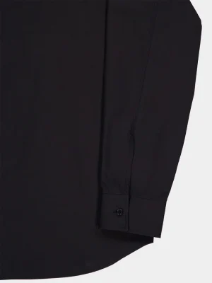 Close-up of a black long-sleeve shirt cuff with a single button and stitched seam detail.
