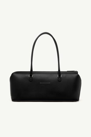 Black leather handbag with two top handles and a top zip closure, resting on a plain light background.