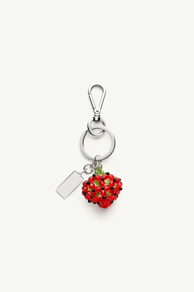 Metal keychain with a red beaded strawberry charm and a small rectangular tag