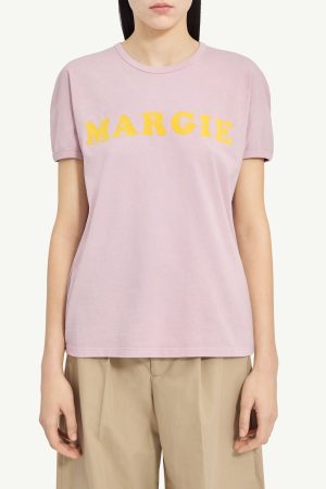 Light pink crew-neck T-shirt with the yellow word 'MARGIE' across the chest, worn by a model in beige pants (informative product image).