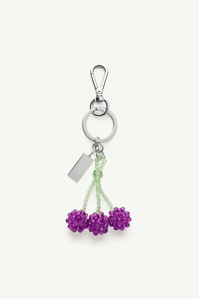 Silver keychain featuring a lobster-claw clasp, a large ring, a hanging lime-green bead stem with three purple bead flowers and a rectangular metal tag.