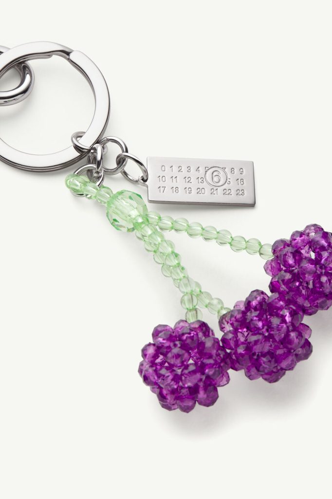 Beaded keychain with green translucent beads and purple crystal clusters on a silver ring and metal engraved tag with numbers.