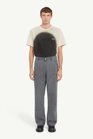 Male model wearing a beige T-shirt with a black gradient circle design and gray cargo pants, standing facing forward.