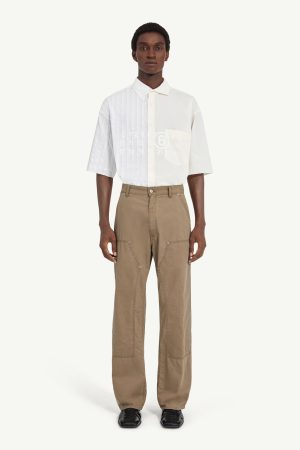 Male model wearing a white short-sleeve button-down shirt with beige cargo pants, standing facing forward with hands at his sides.