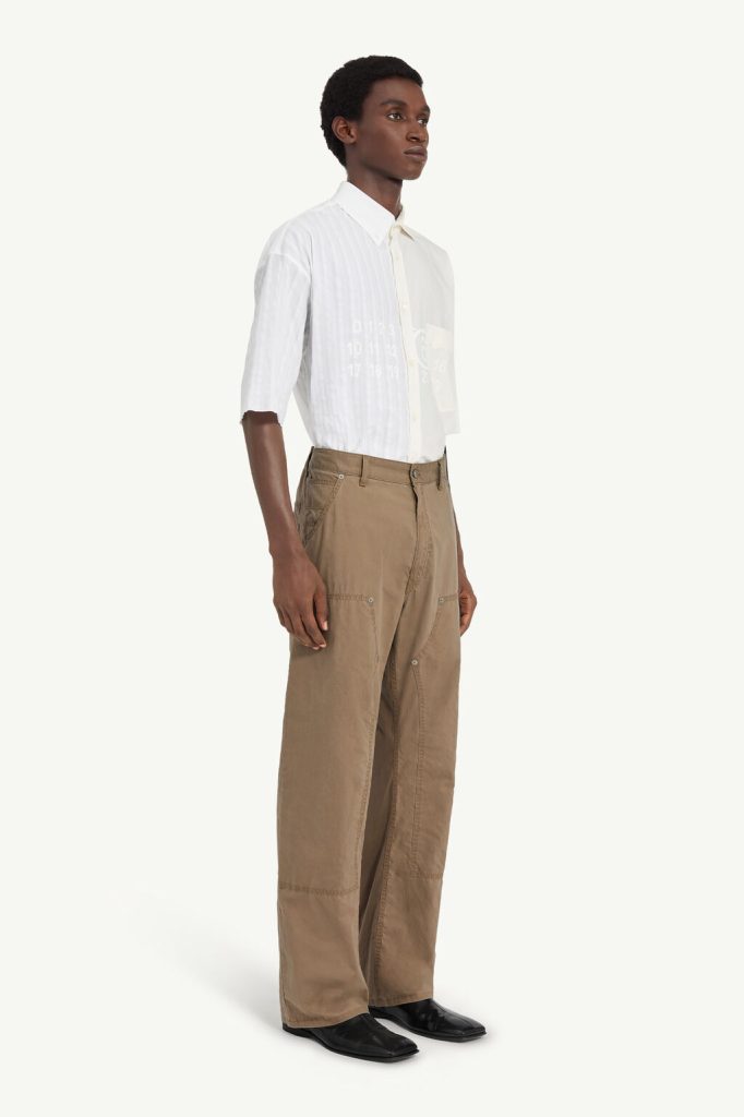 Male model in a white button-down shirt and tan wide-leg cargo pants, standing against a pale background with black shoes.