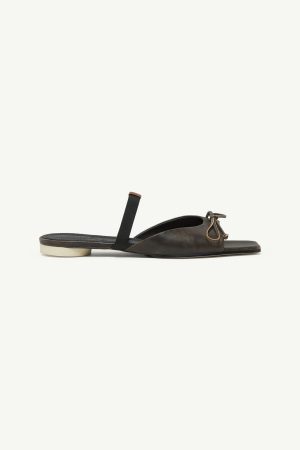Dark brown leather slide sandal with an open toe, back strap, and a small bow knot at the front over a light-colored sole.