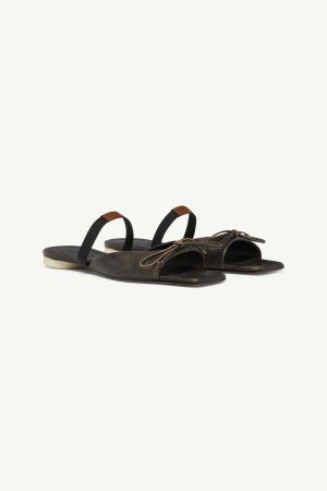 Dark brown leather slide sandals with black fabric back straps and tan lace details on a light background