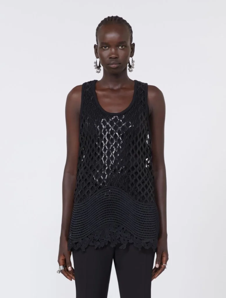 Woman modeling a black sleeveless mesh top with lattice pattern and scalloped lace hem.