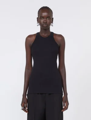 Front view of a tall woman wearing a black sleeveless ribbed tank top and black wide-leg pants, posing against a plain light background.