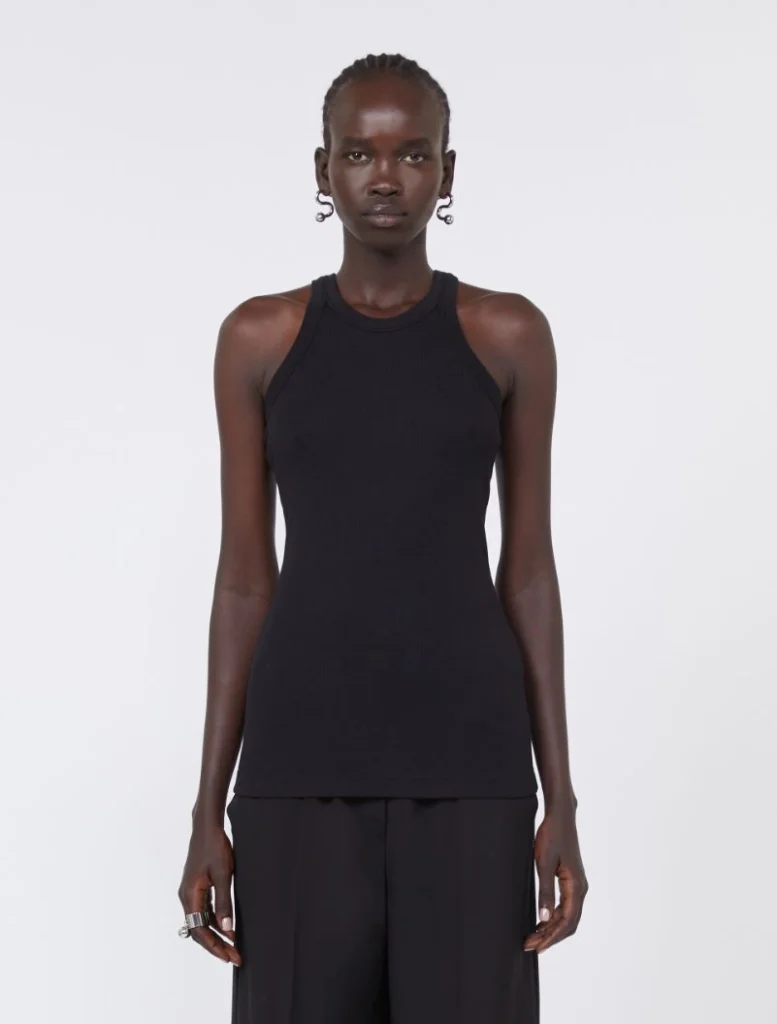 Front view of a tall woman wearing a black sleeveless ribbed tank top and black wide-leg pants, posing against a plain light background.
