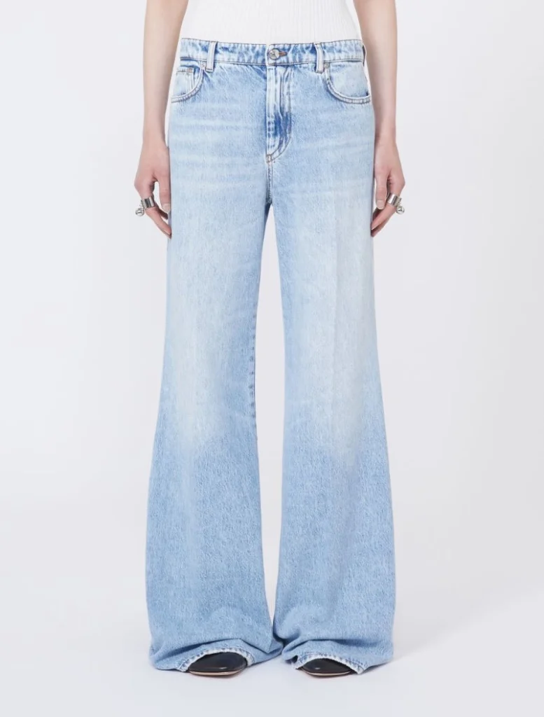 Full-length, light-wash wide-leg denim jeans on a model with a white top in a neutral studio setting.