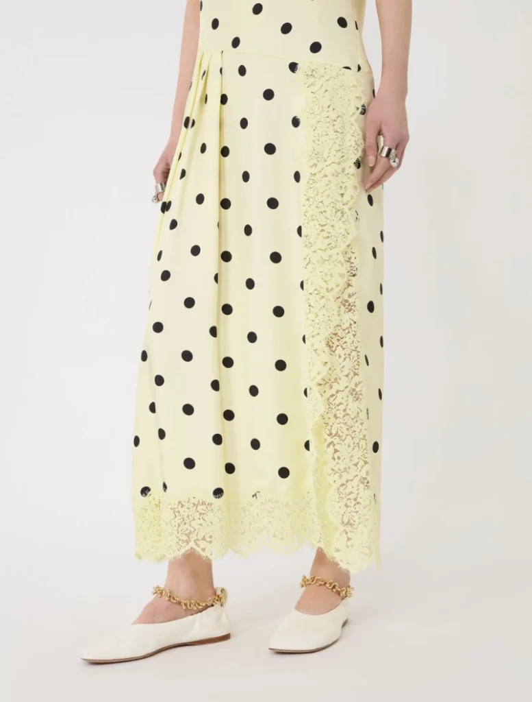 Yellow polka-dot maxi dress with lace side panel and scalloped lace hem, paired with white flats and gold chain ankle bracelets.