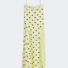Yellow polka-dot spaghetti-strap maxi dress with lace trim at the hem.