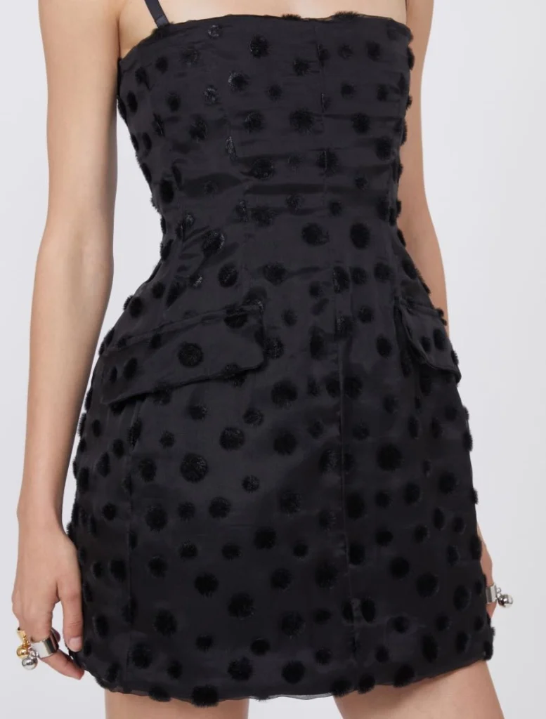 Black mini dress with fuzzy polka-dot texture and front pockets on a model's torso.