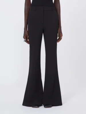 Person wearing black high-waisted wide‑leg trousers with a tailored fit, standing against a light background.