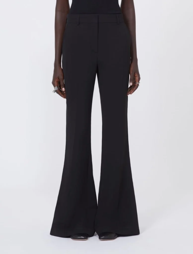 Person wearing black high-waisted wide‑leg trousers with a tailored fit, standing against a light background.
