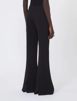Back view of a model wearing black high-waisted wide-leg trousers with long flared hems.