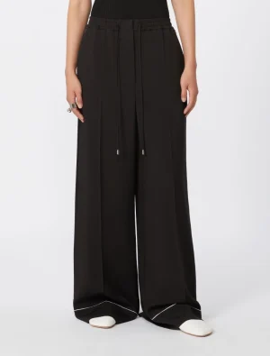 Full-length black wide-leg pants with an elastic drawstring waist, worn with white shoes.