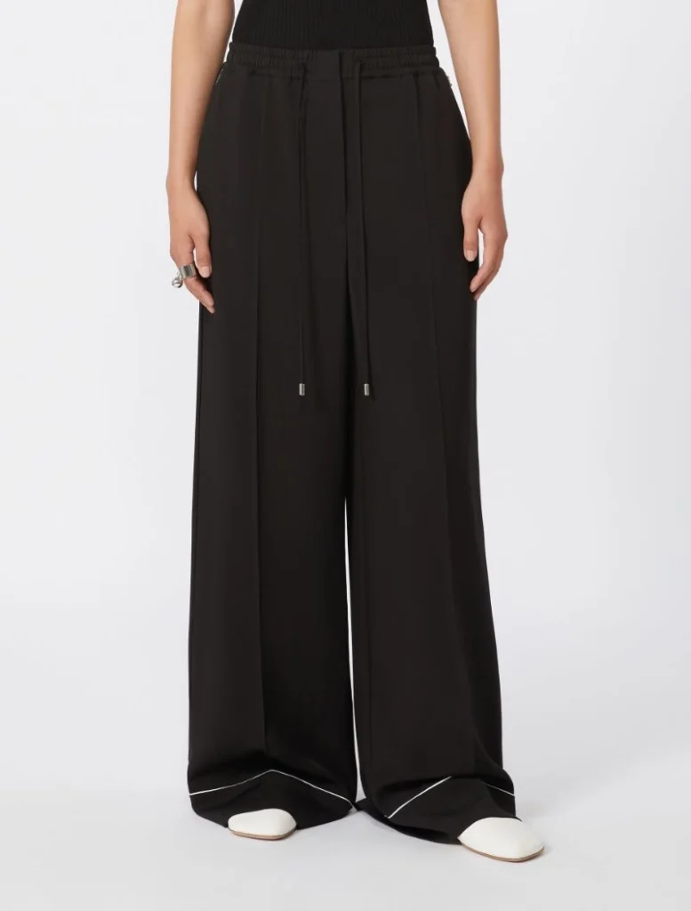 Full-length black wide-leg pants with an elastic drawstring waist, worn with white shoes.