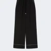 Black wide-leg pants with a drawstring waist and white piping along the hem.