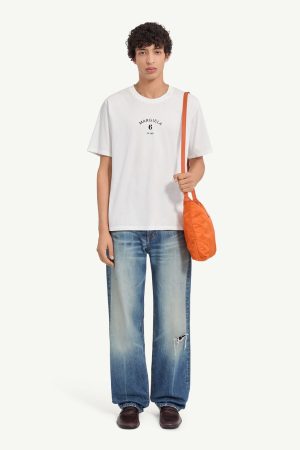 Man wearing a white oversized T-shirt, baggy ripped jeans, brown loafers, and an orange crossbody bag over the shoulder (full body).