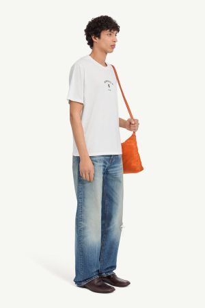 Young man in a white T-shirt and loose blue jeans, carrying an orange crossbody bag, shown in profile.