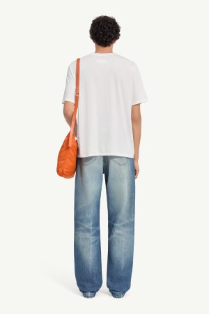 Back view of a person in a white T-shirt and baggy blue jeans, carrying an orange shoulder bag.