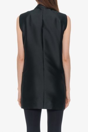 Back view of a sleeveless black tunic top with a center back seam, worn over black leggings.