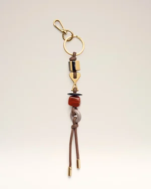 Gold keychain with a circular ring, brown leather cord, and amber beads hanging against a light background.