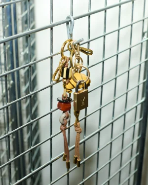 Close-up of a metal grid with hanging keychains and keys in gold and brown tones many rings.