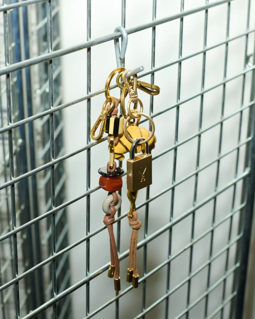 Close-up of a metal grid with hanging keychains and keys in gold and brown tones many rings.