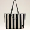 Striped beige and black tote bag with long black handles and a small heart patch near the bottom corner.