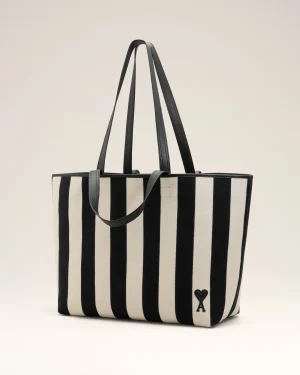 Black and white striped tote bag with grey handles standing upright against a light background, showing a small X logo near the bottom corner.