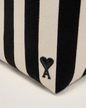Close-up of beige and black vertical striped fabric with a small black heart patch near the bottom edge.