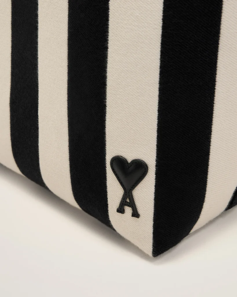Close-up of beige and black vertical striped fabric with a small black heart patch near the bottom edge.