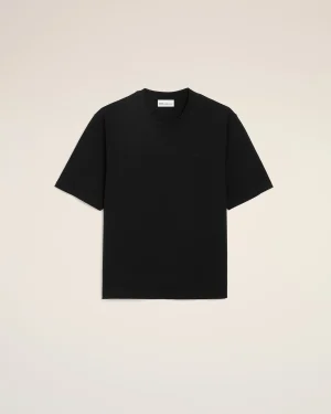 Black short-sleeve T-shirt laid flat on a beige background, front view.