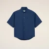 Blue short-sleeve button-down shirt with a front pocket on a cream background.