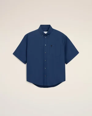 Blue short-sleeve button-down shirt with a front pocket on a cream background.