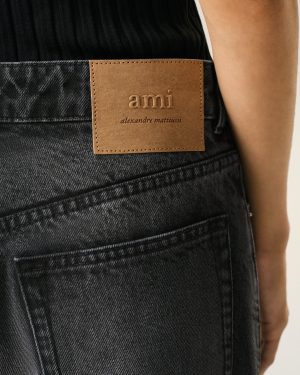 Back of dark denim jeans with a tan leather brand patch reading 