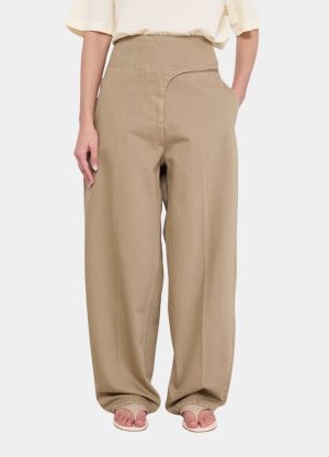 Beige wide-leg high-waisted pants on a model, paired with a light cream top and sandals.