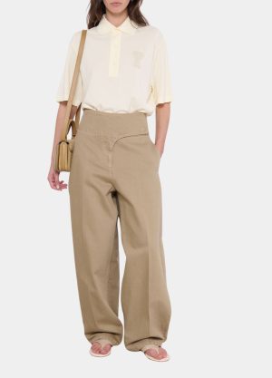 Woman wearing a cream polo tucked into oversized beige wide-leg pants, tan crossbody bag, and sandals.