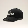 Black baseball cap with white cursive lettering on the front panel, photographed against a light backdrop.